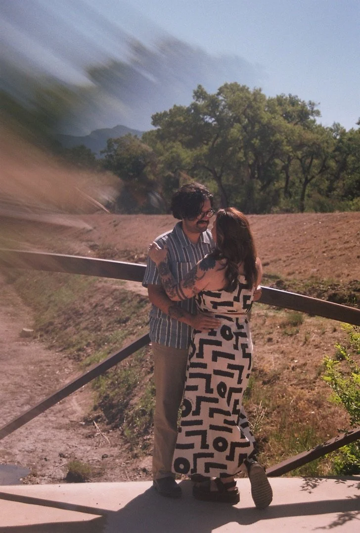 Engaged couple embracing on a bridge during a 35mm film engagement session at Corrales Bosque Open Space near Albuquerque, New Mexico.