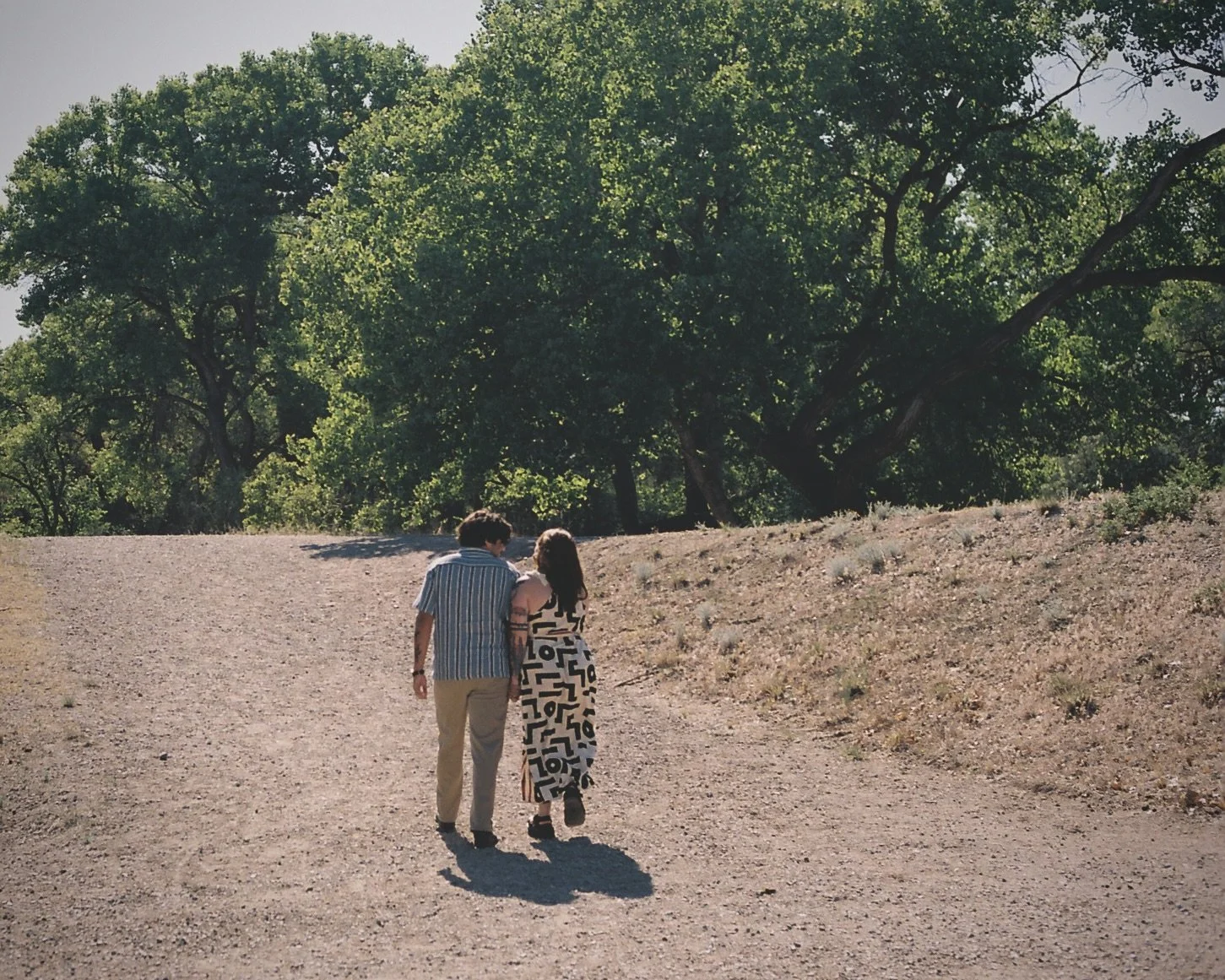 Engaged couple walking together during a 35mm film engagement session at Corrales Bosque Open Space near Albuquerque, New Mexico.