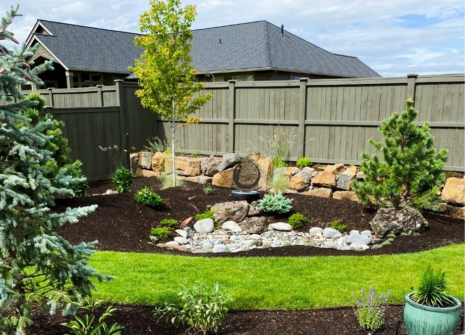 Stunning backyard landscape with trees, mulch, plants, boulders and edged lawn as part of Bend Oregon landscape construction