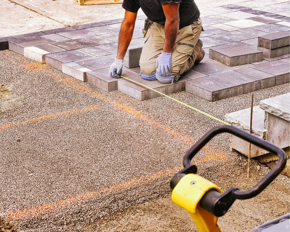 Landscape construction company worker installing custom paver patio
