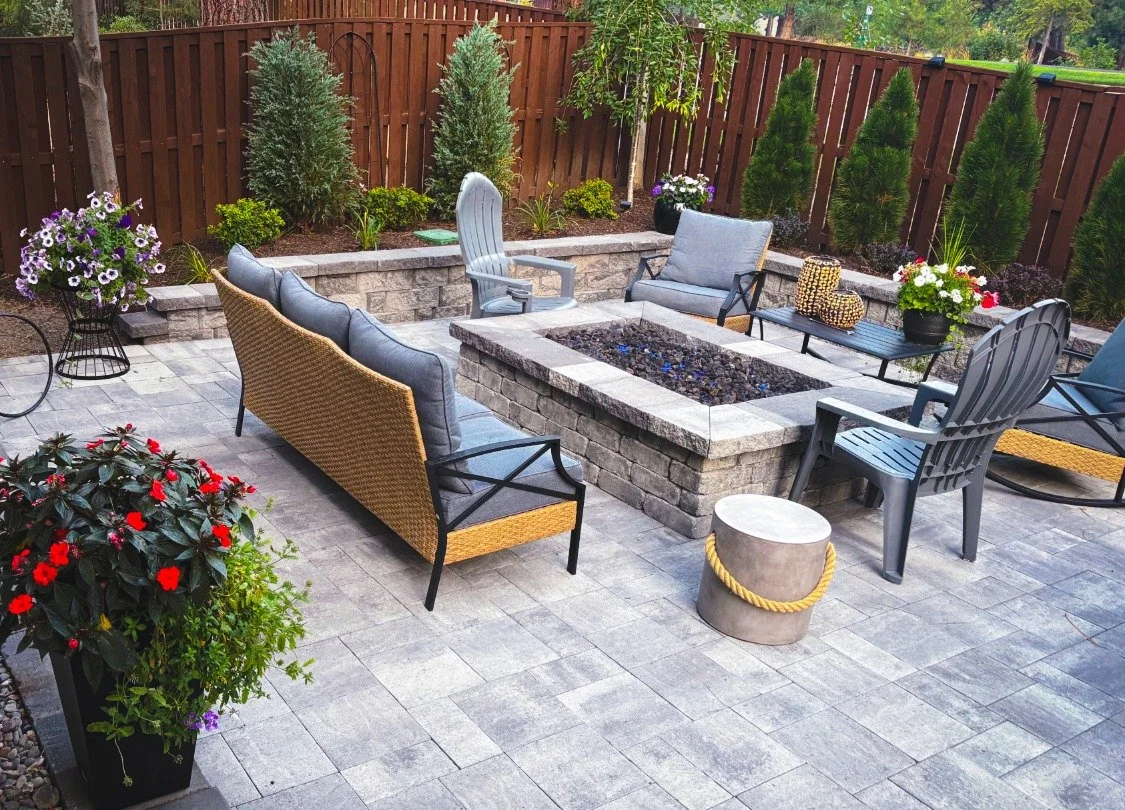 Seating area and custom built stone fireplace surrounded by plants and trees for a Bend Oregon landscape cosntruction