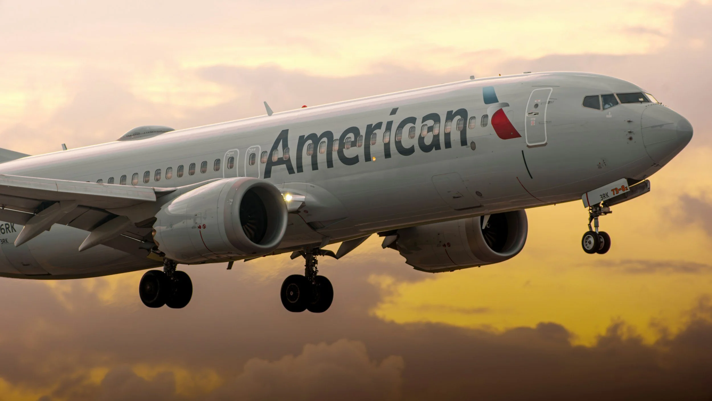 An American commercial airplane in flight during sunset, with the word 'American' on its side.
