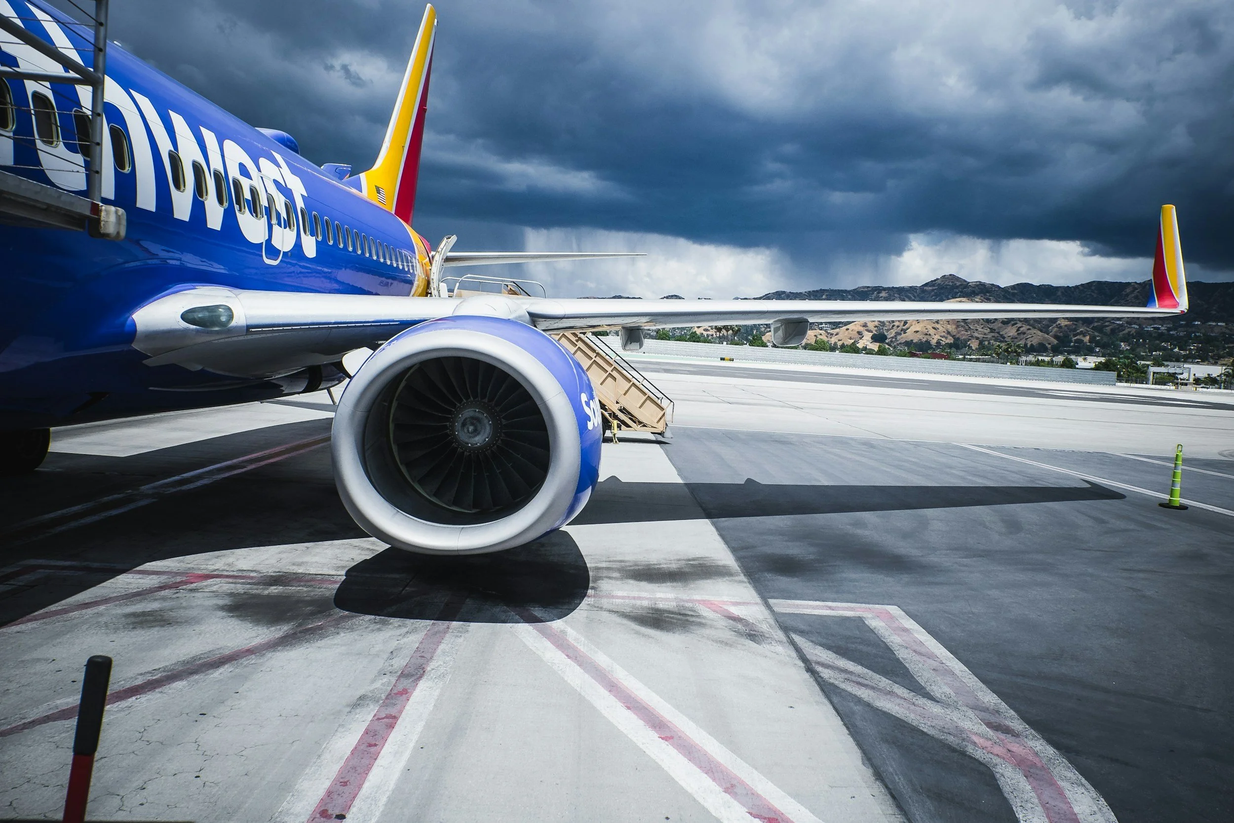 Front view of a Southwest Airlines airplane parked at the gate on a cloudy day, with mountains in the distance.