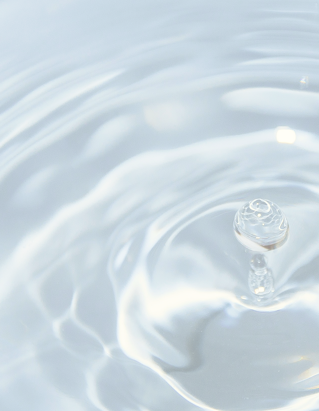 Close-up of a water droplet creating ripples on a calm water surface.