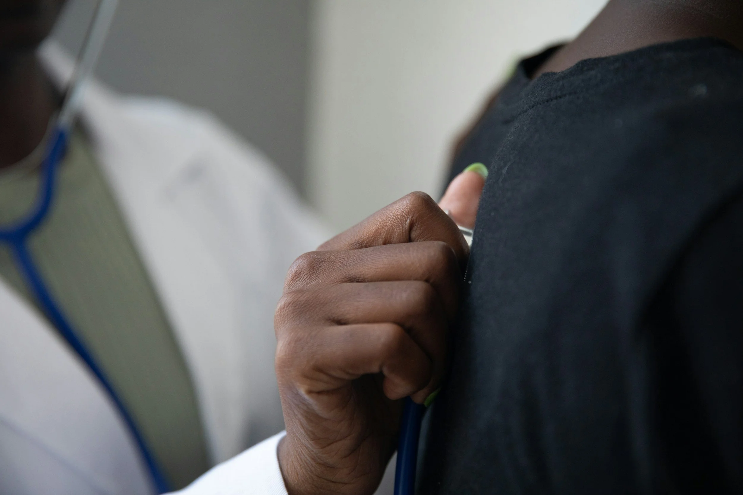 A person holding a blue cable with their left hand, wearing a dark shirt, with their thumb and index finger gripping the cable.