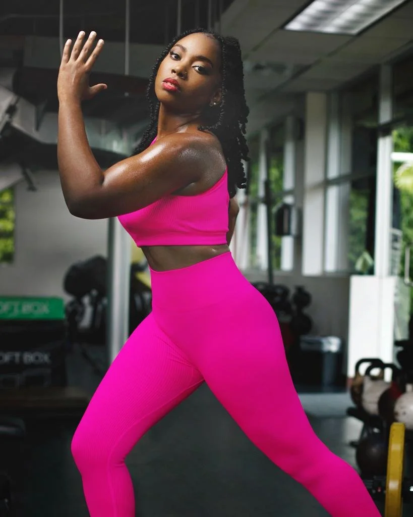 A woman in pink workout clothing posing in a gym.