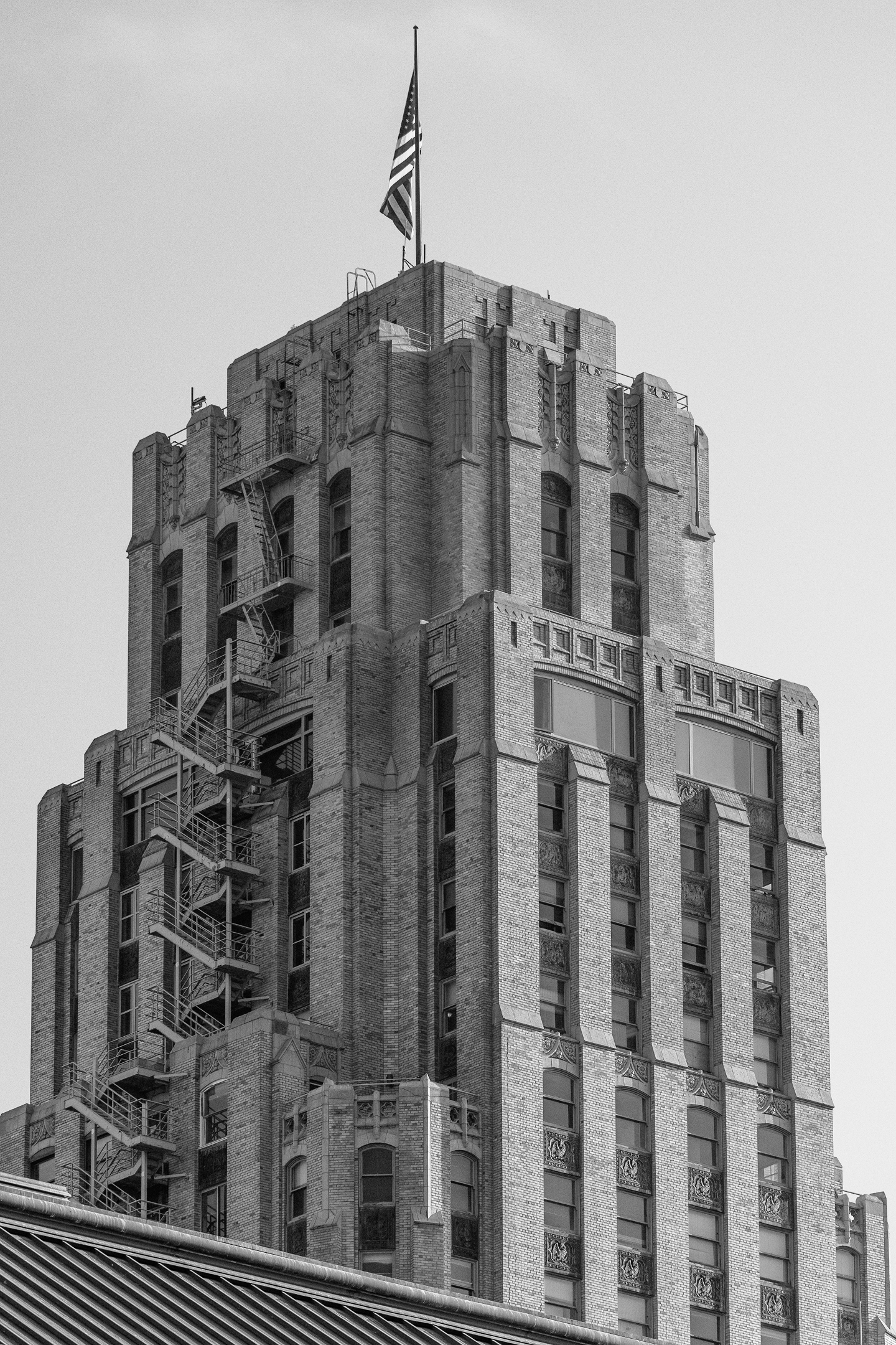 A tall skyscraper with brick exterior and ornate decorative elements, topped with an American flag flying at the top.