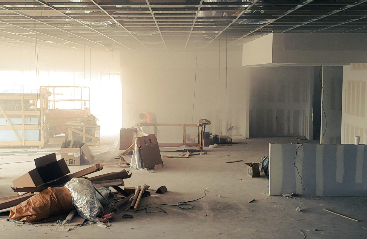 Interior under construction with scattered building materials, tools, and construction debris.