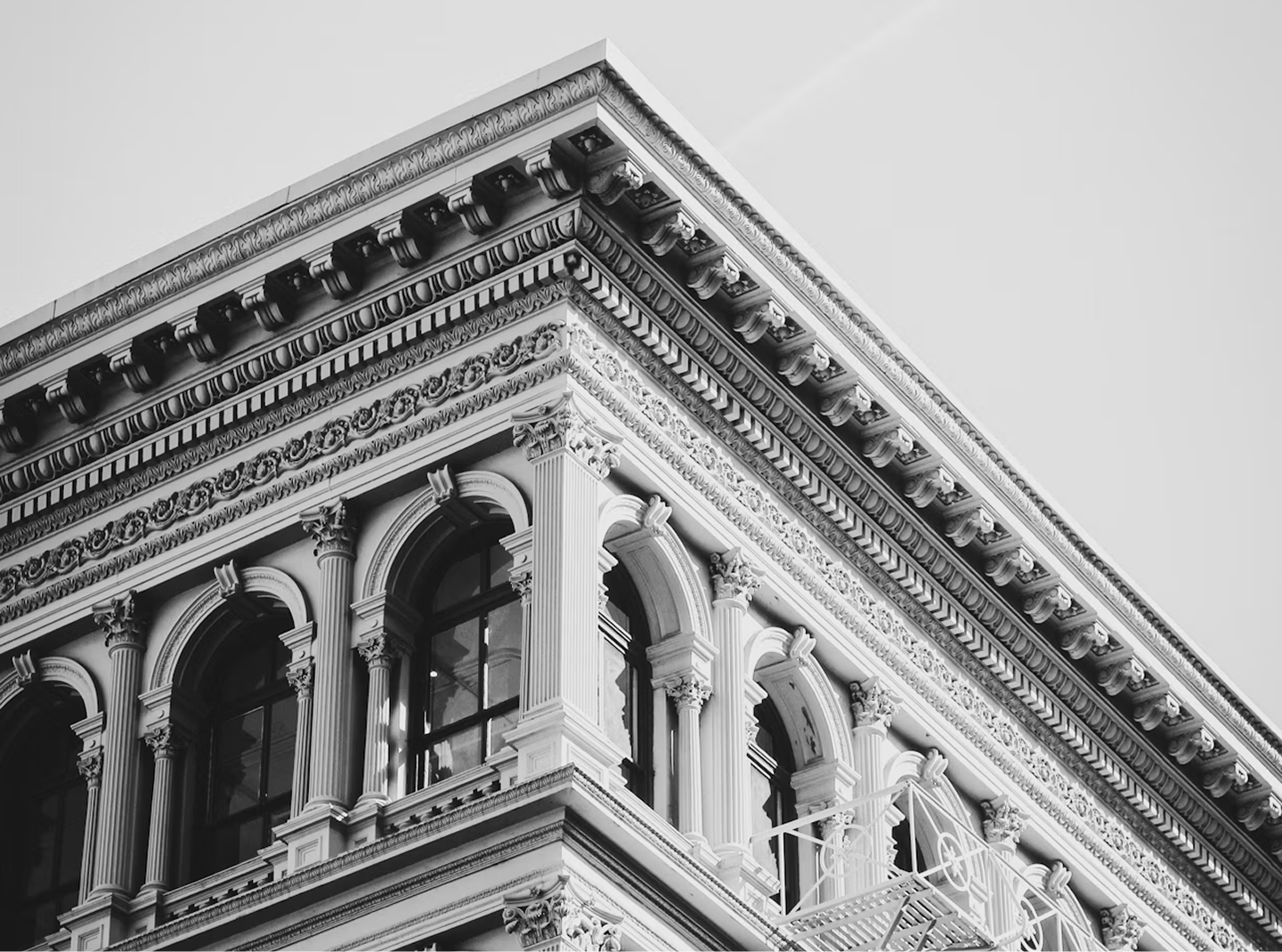 Black and white photograph of a historic building with intricate architectural details, including arched windows, decorative columns, and ornate cornices.