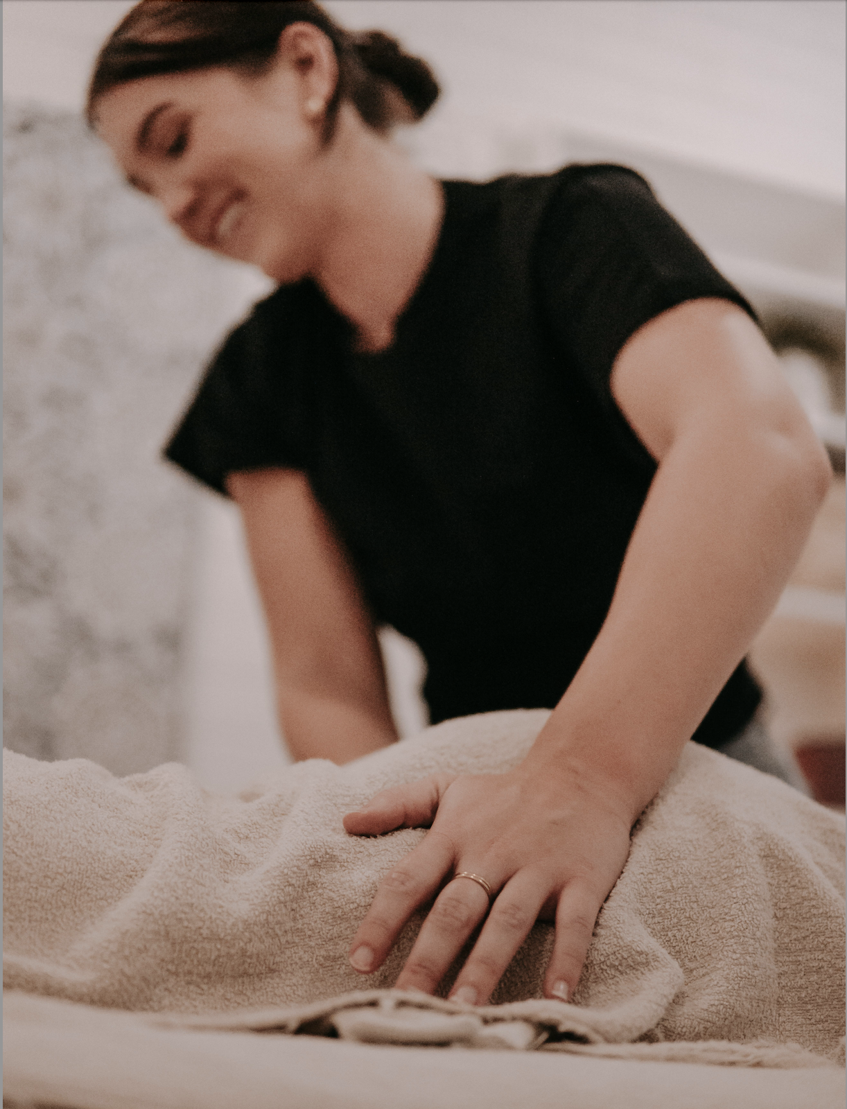 A woman in a black shirt performing chest compressions during a CPR training session, seen from the side with blurred focus.