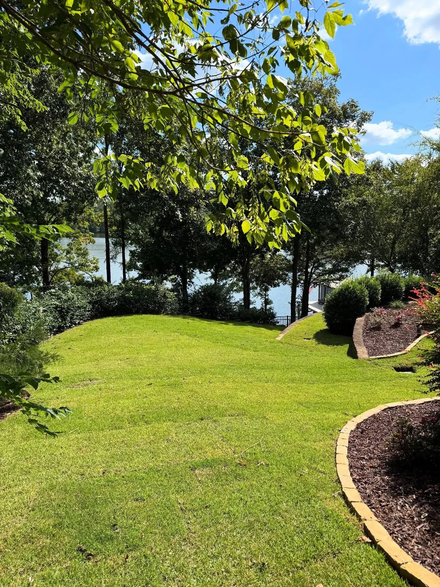 Yard with mulched garden beds with stone paver borders on a lake-front property