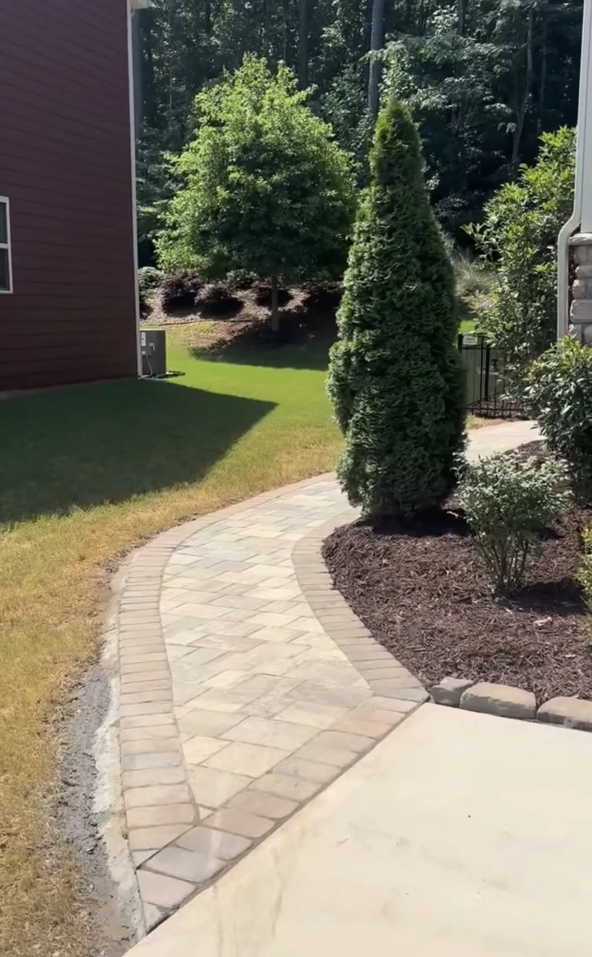 Stone walkway with shrubs by a mulched bed