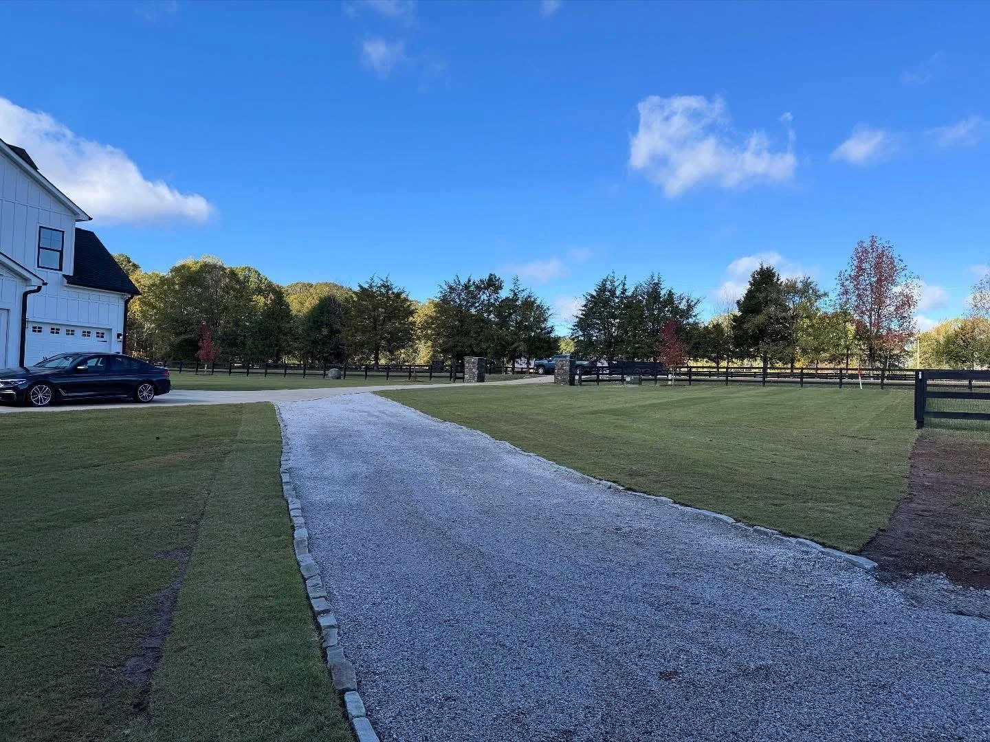 Gravel driveway with stone border surrounded by freshly laid sod