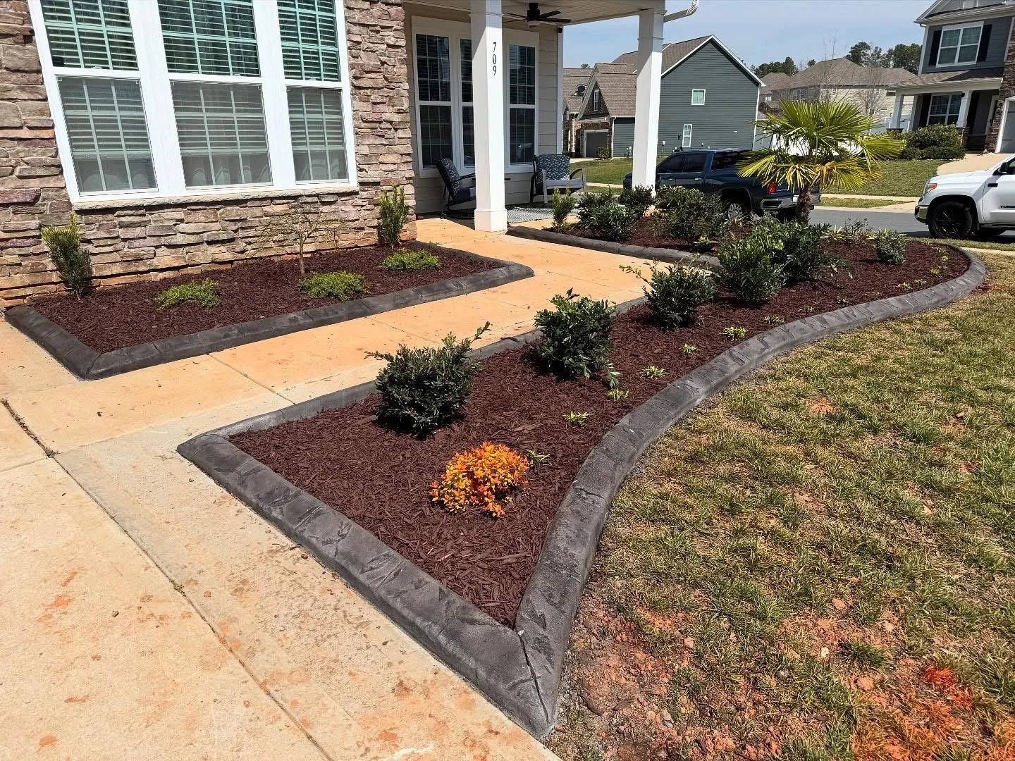 Mulched garden bed with perennial plants and stone border