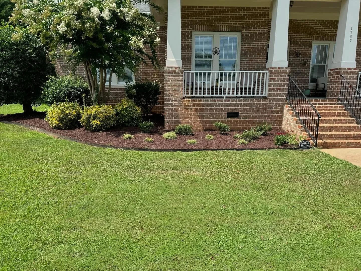 Mulched garden bed and green grass in front of house