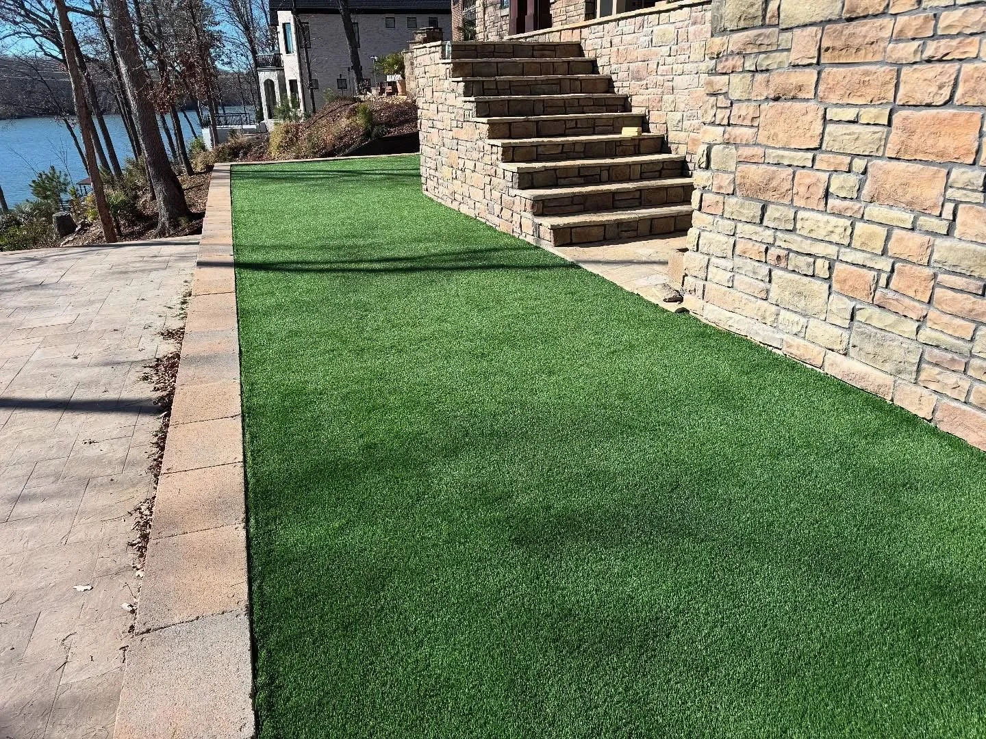 Artificial turf in front of stone patio and stairs at lakefront property
