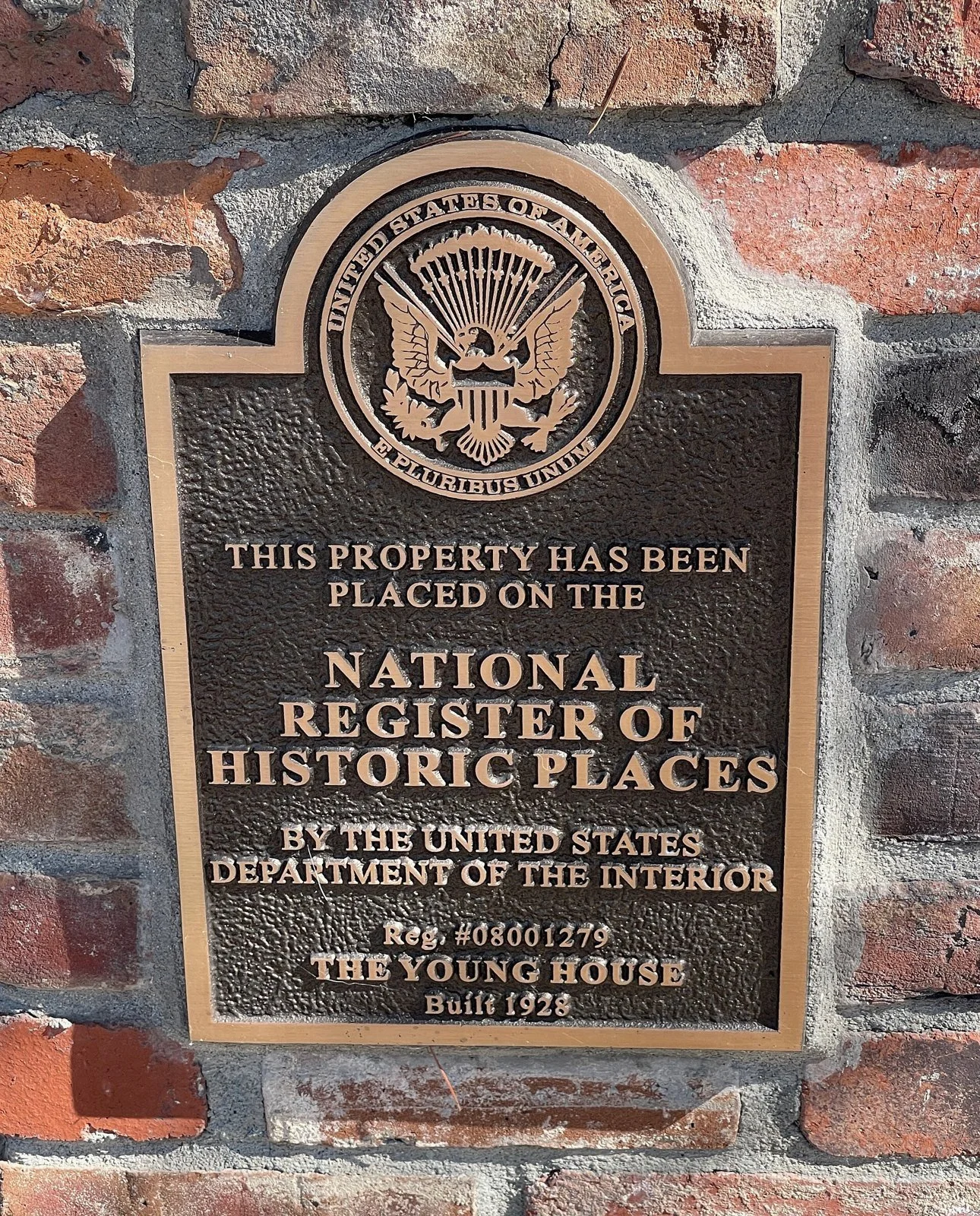 A bronze National Register of Historic Places plaque mounted on a brick wall, with raised lettering and an eagle emblem.