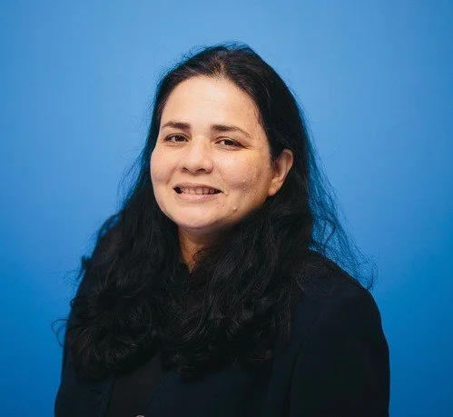 Portrait of a woman with long dark hair against a blue background.