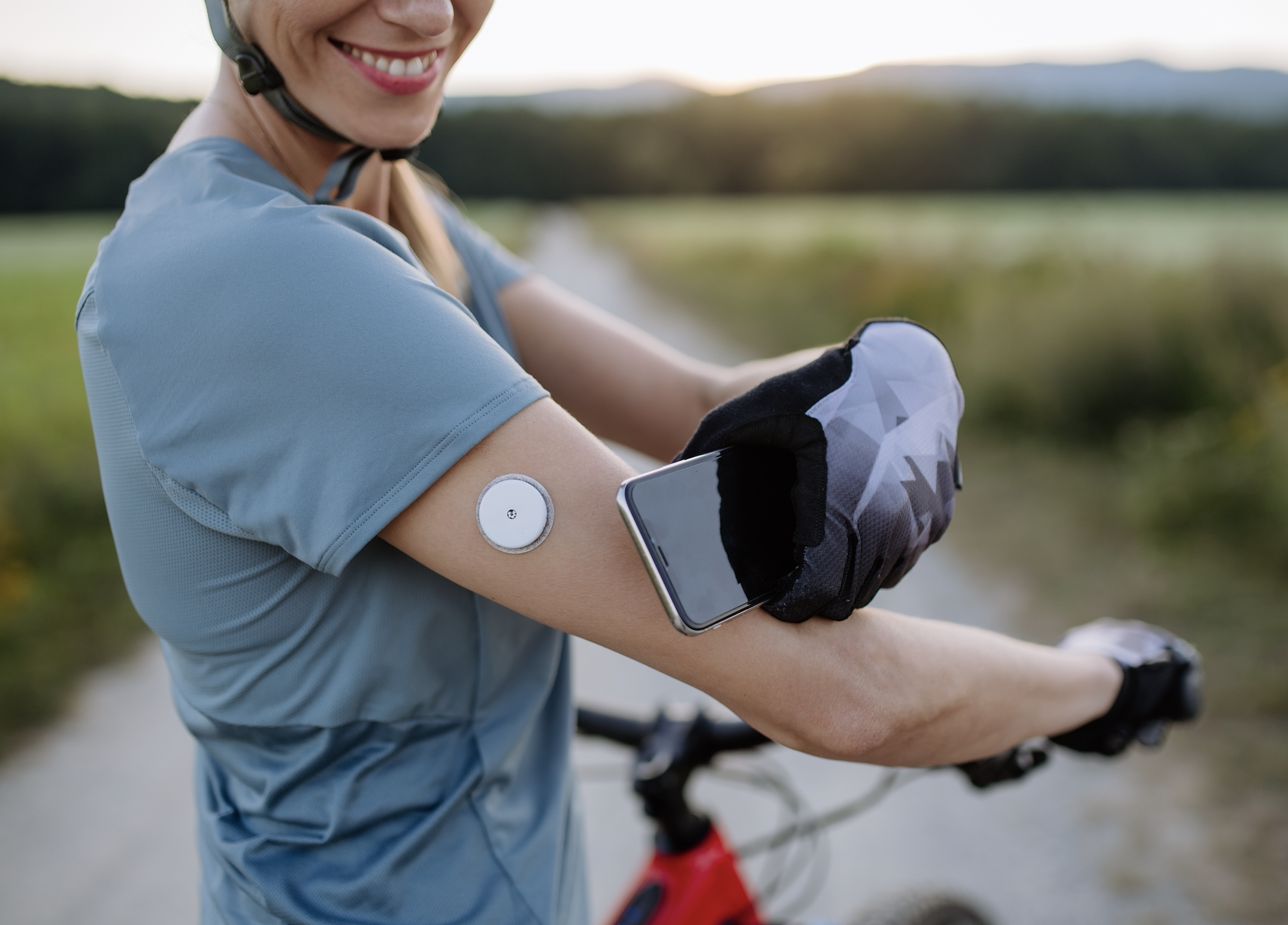 Person riding a bike while checking their continuous glucose monitor (CGM).