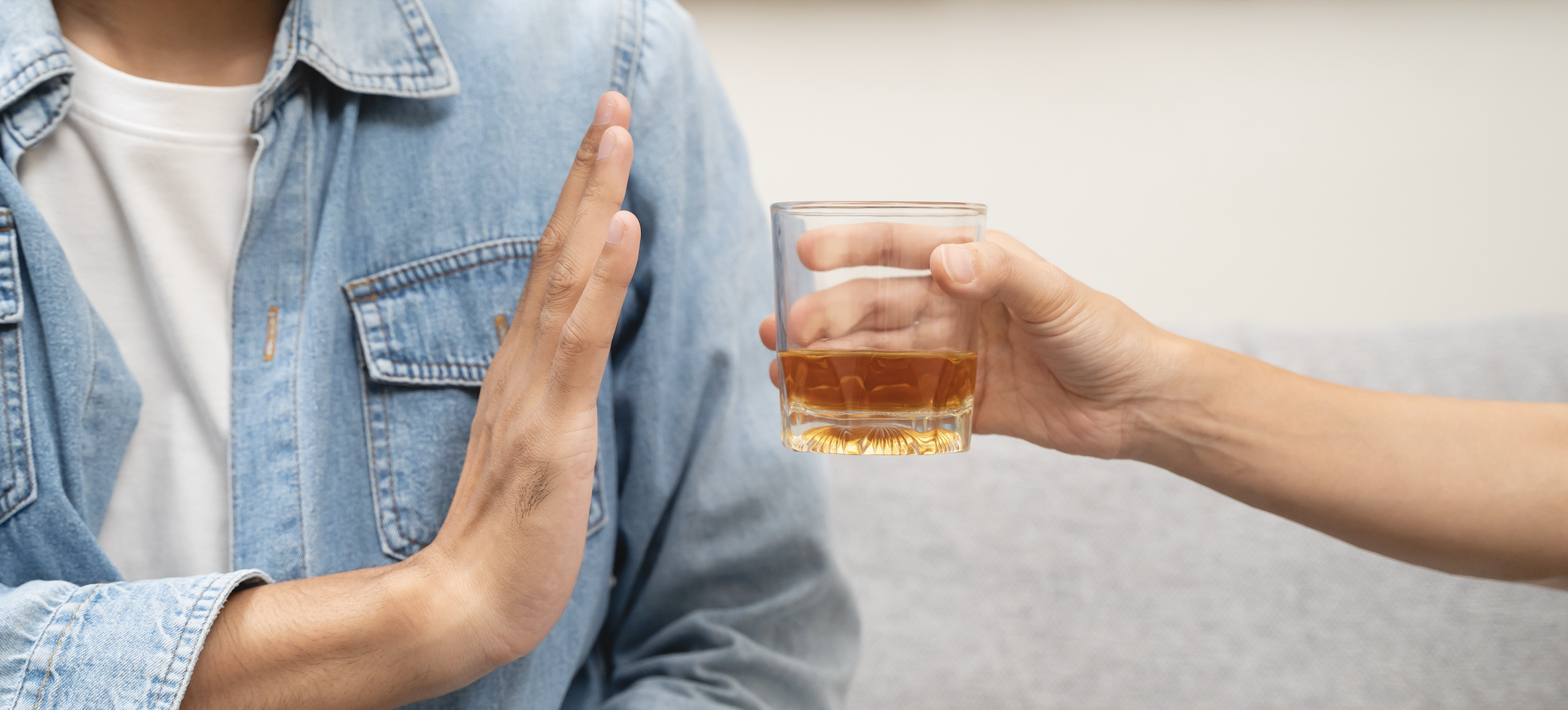 Person holding up hand to say no to an offered drink.