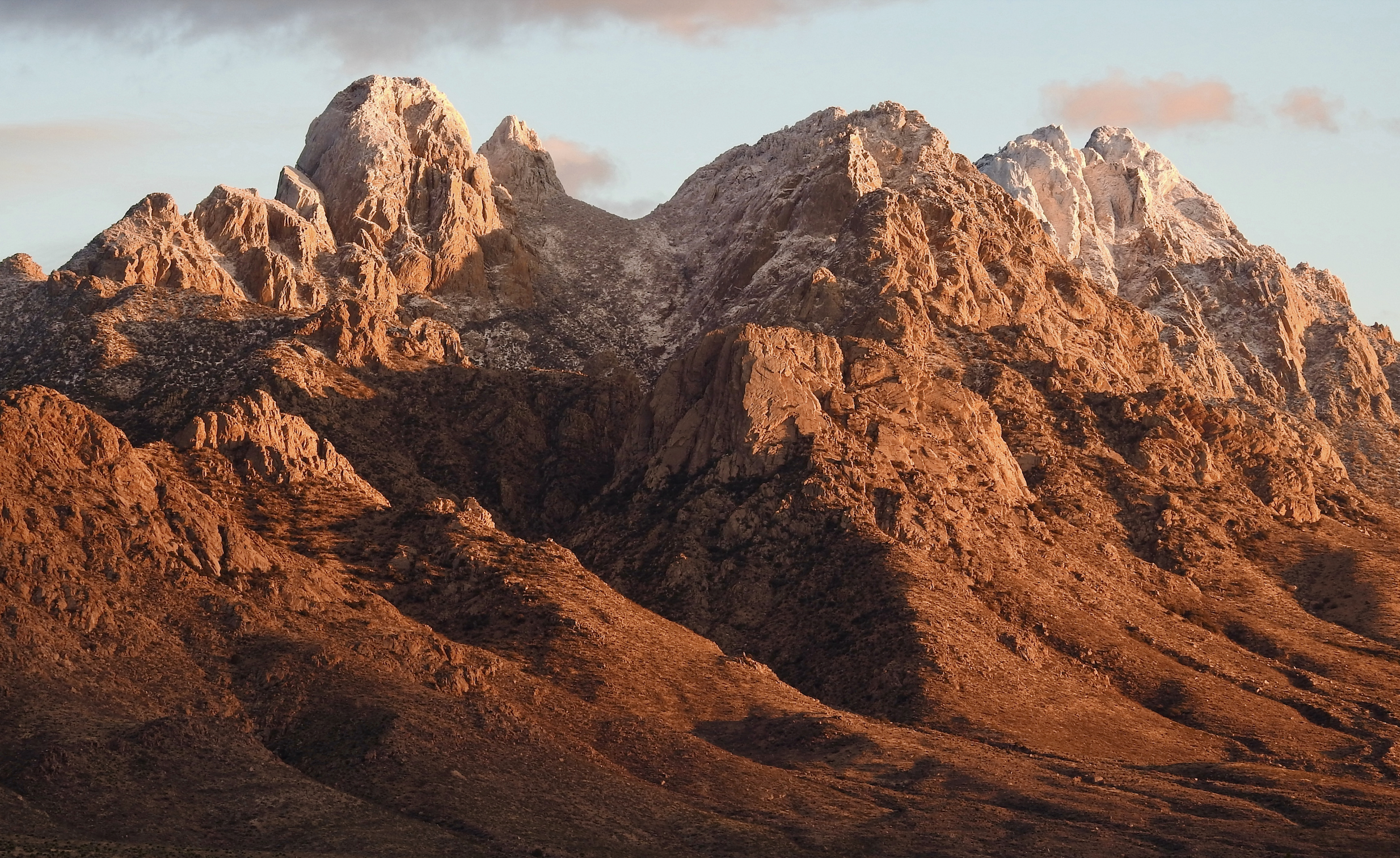 Brilliant orange sunset casting warm light over the rugged Organ Mountains.