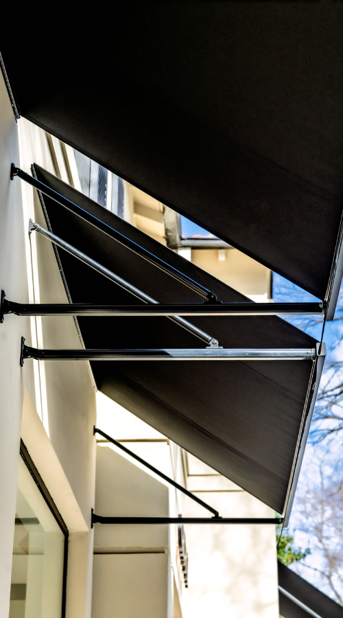 Black awnings attached to the exterior of a building, extending outward to provide shade.