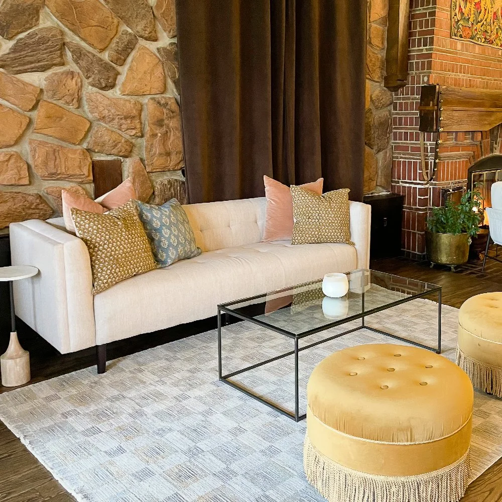 A Cozy Wedding Reception Lounge Rental, White Couch, Beige Patterned Rug, Pink and Gold Pattern Pillows, Glass Coffee Table, Yellow Ottoman