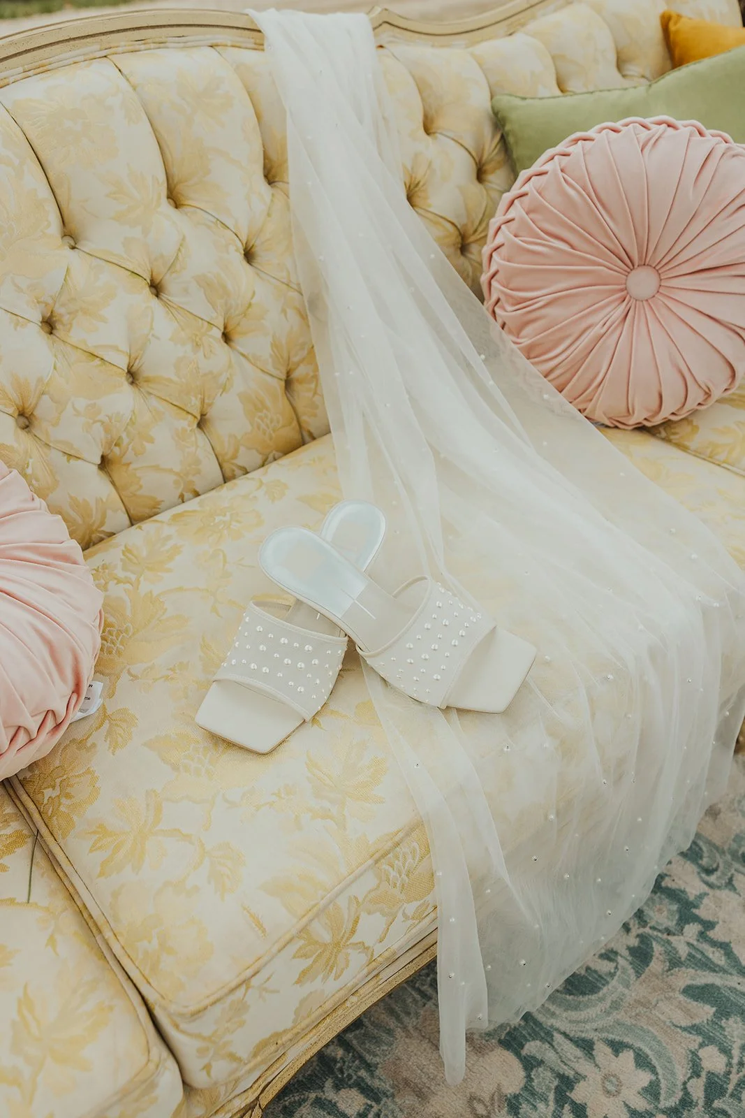 A Wedding Reception Lounge Styled By Mountain Arrow Events and Rentals with White High Heels, Yellow Vintage Couch, and Pink Pillows
