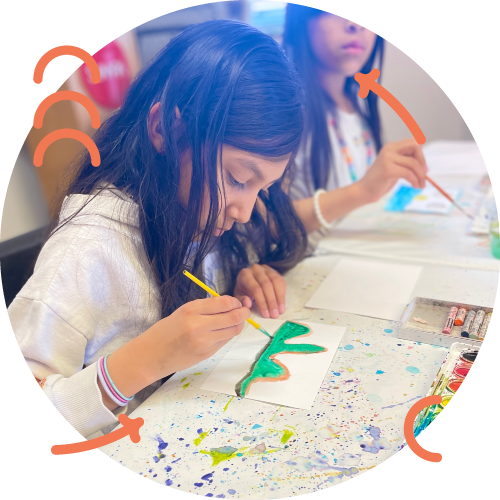 Two children painting at a table with colorful paint splatters and art supplies, focusing on their artwork.