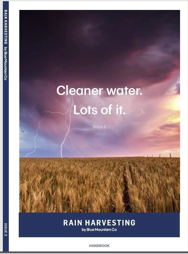 Cover of a handbook titled 'Rain Harvesting' by Blue Mountain Co, featuring a field of wheat under a stormy sky with lightning and sunset hues.