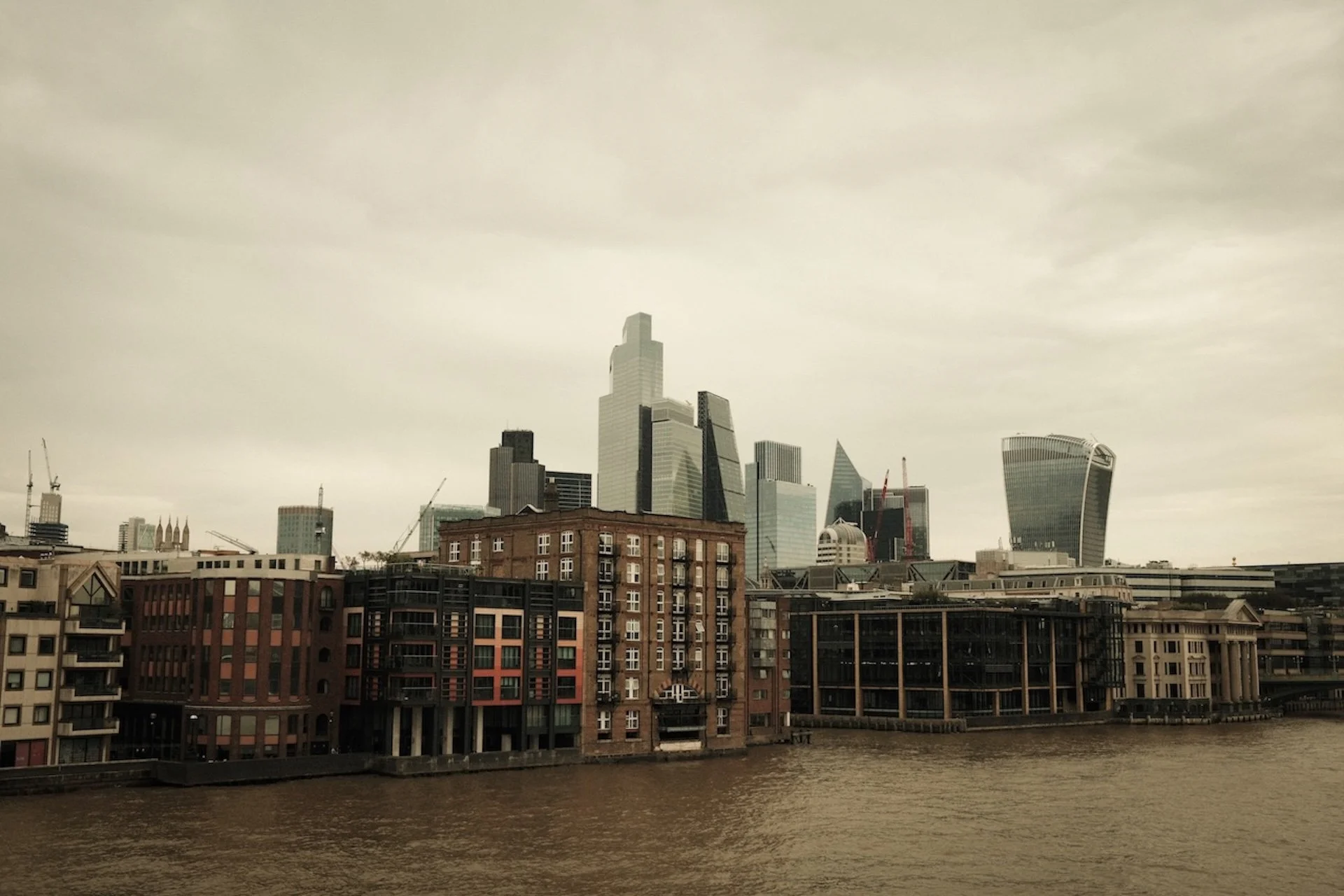 City skyline with modern skyscrapers over a river on a cloudy day.