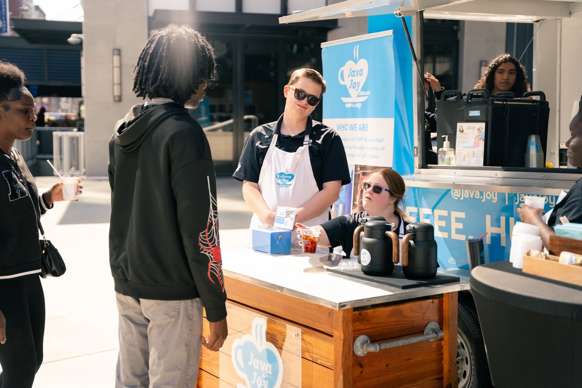 People ordering and being served coffee at a Java Joy coffee stand.