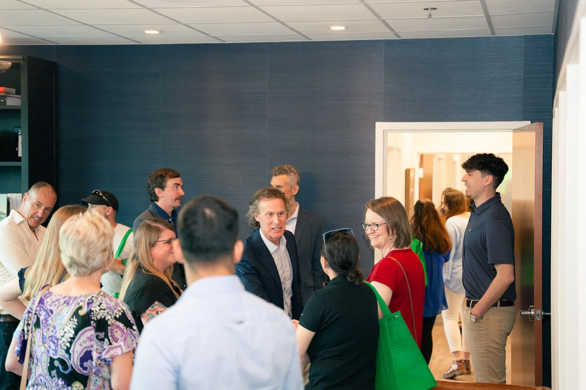 Group of people engaged in conversation at an indoor social event or networking gathering.