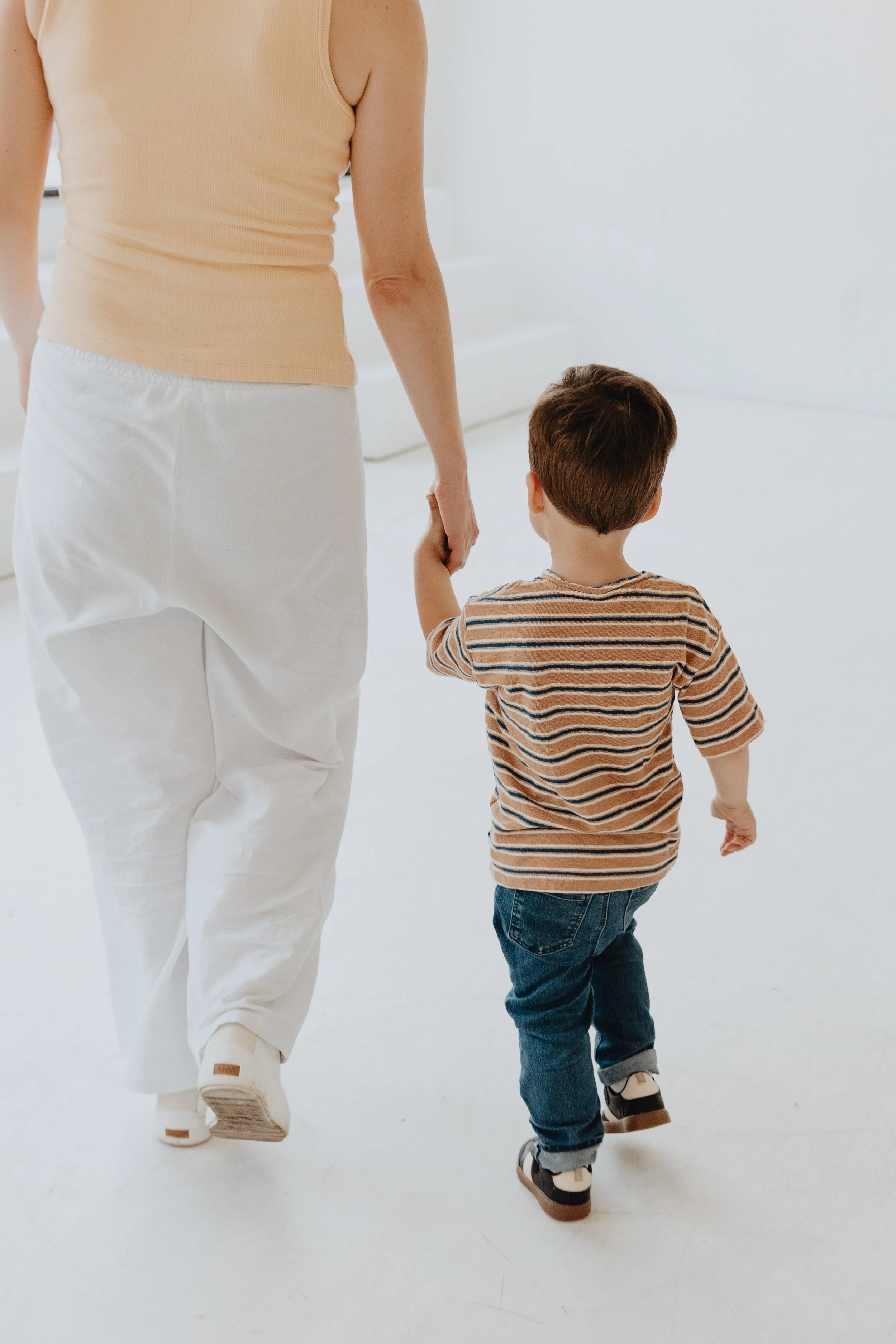 Toddler and adult holding hands and walking