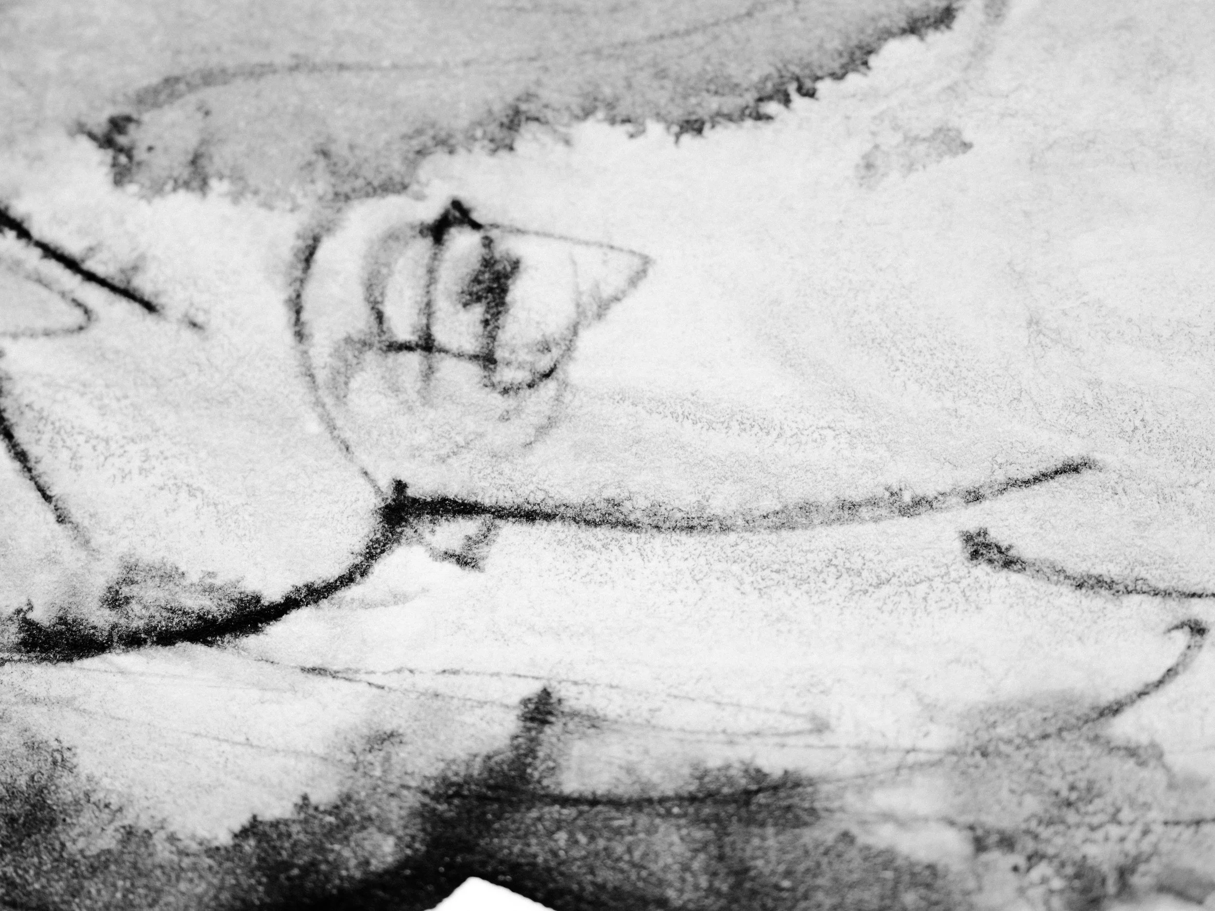 Close-up of a hand sketching on paper with a pencil, with a drawn circular shape and some lines.