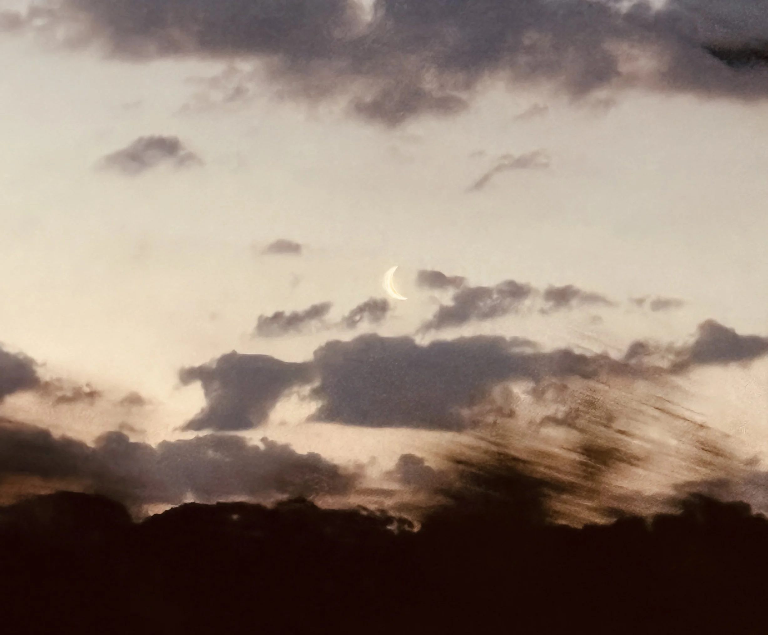 Nighttime sky with clouds and a visible crescent moon.