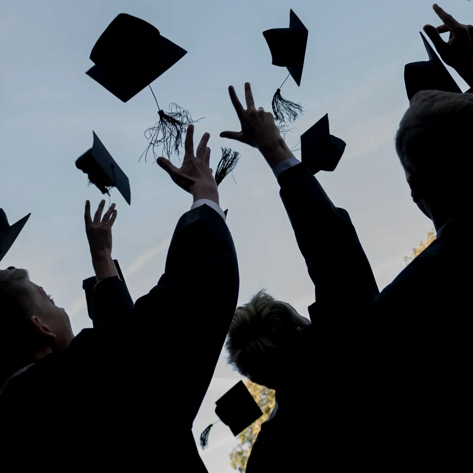 People in graduation gowns tossing their caps into the air during the graduation ceremony.