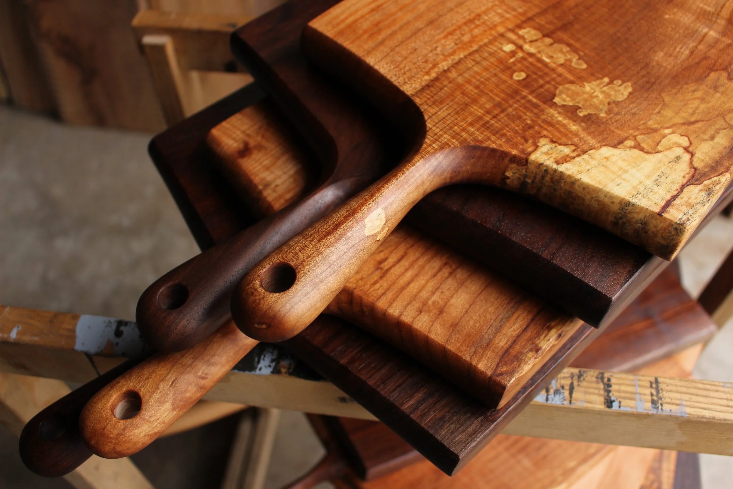 Wooden cutting boards with two wooden handles placed on a rustic wooden surface.