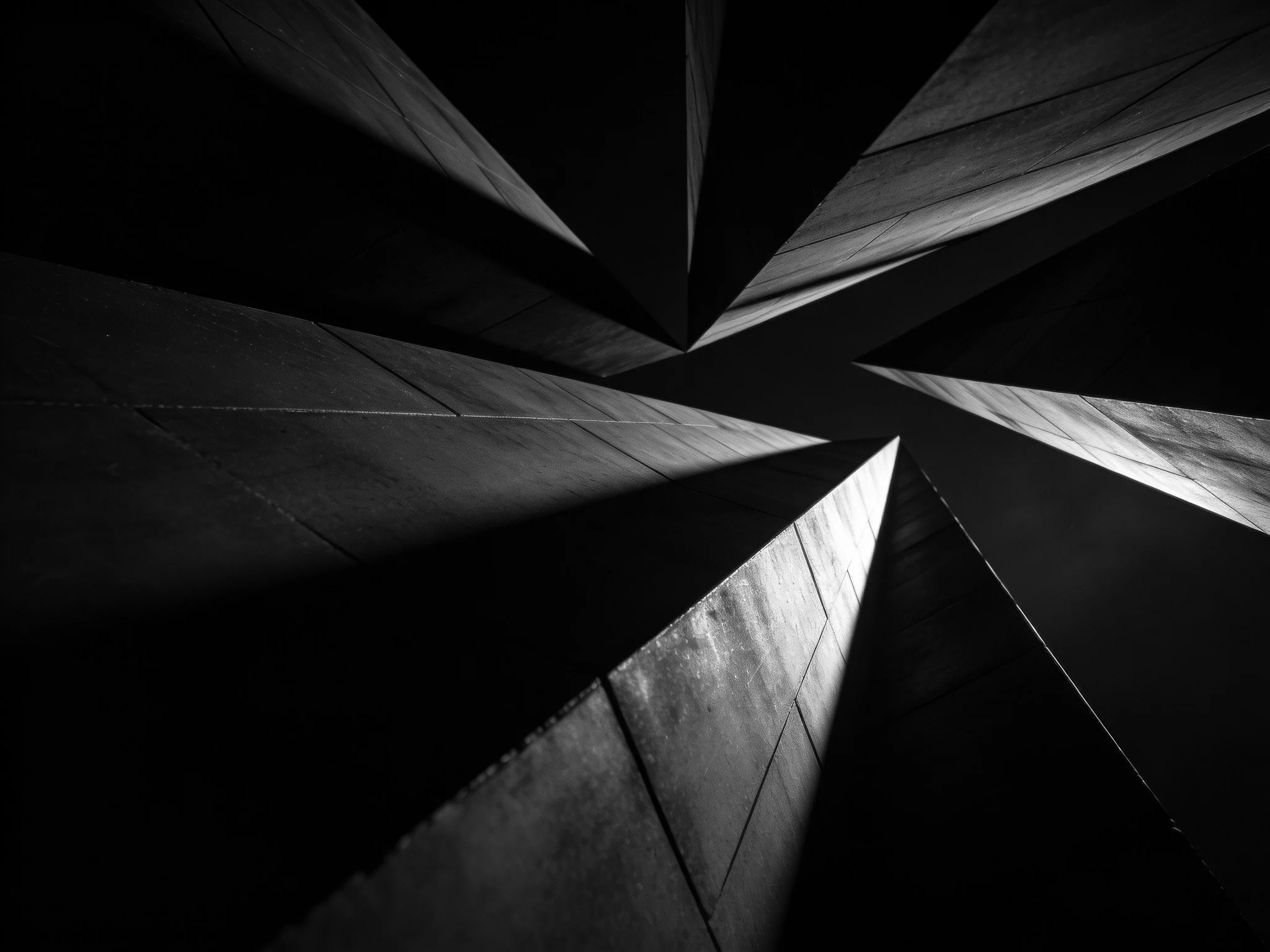 Abstract black and white image of geometric, pointed concrete structures viewed from below.
