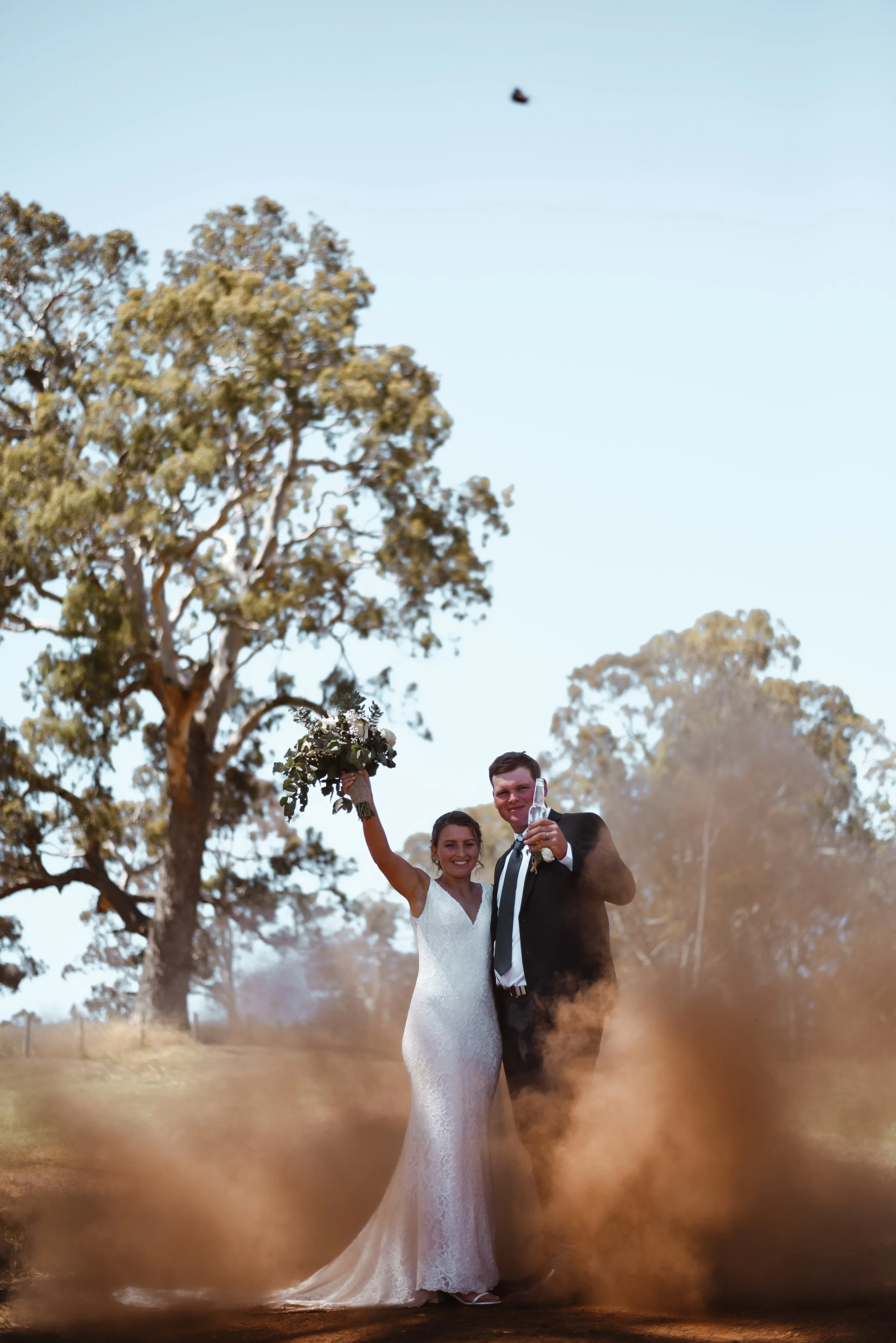 couple cheering to being married while red dirt flys around them