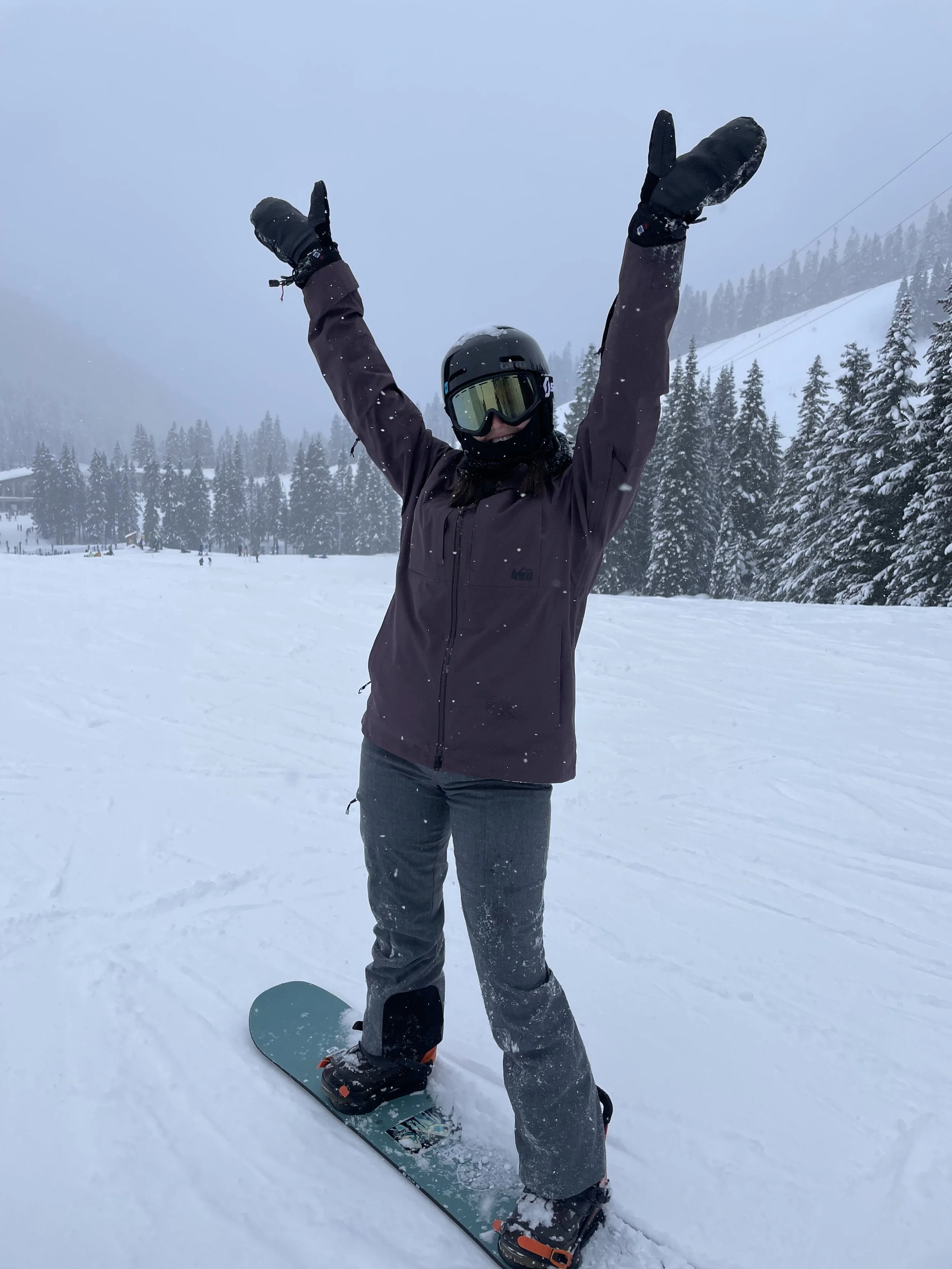 Person in black helmet and snowboard gear smiling on snowy mountain
