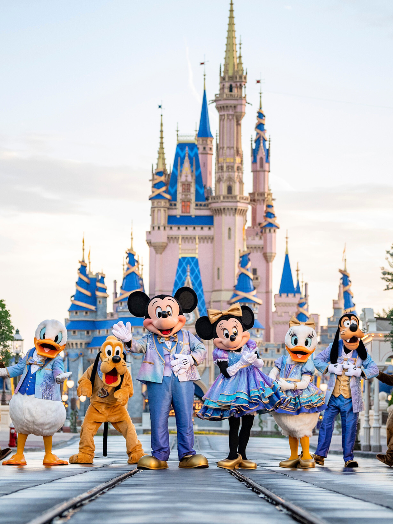 Personajes de Disney, incluyendo a Mickey Mouse, Minnie Mouse, Donald y Daisy Duck, posando delante del castillo de Disneyland.