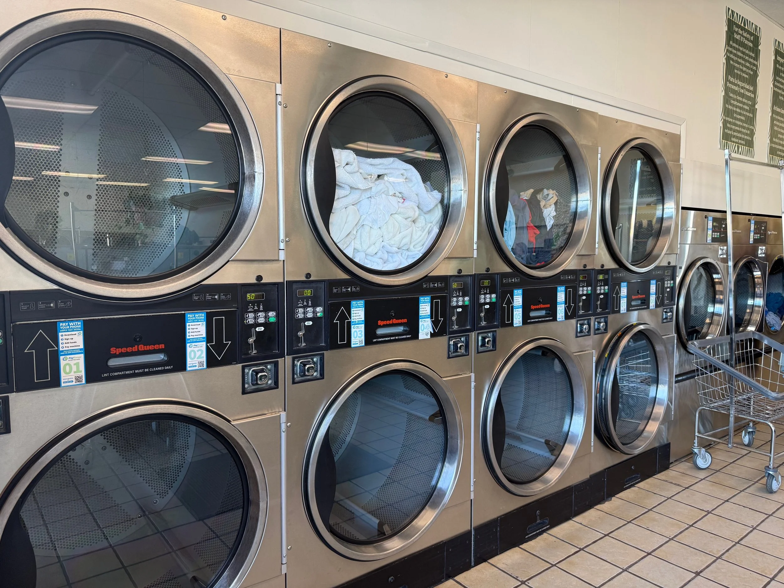 Commercial laundry room with empty and filled industrial washing machines.