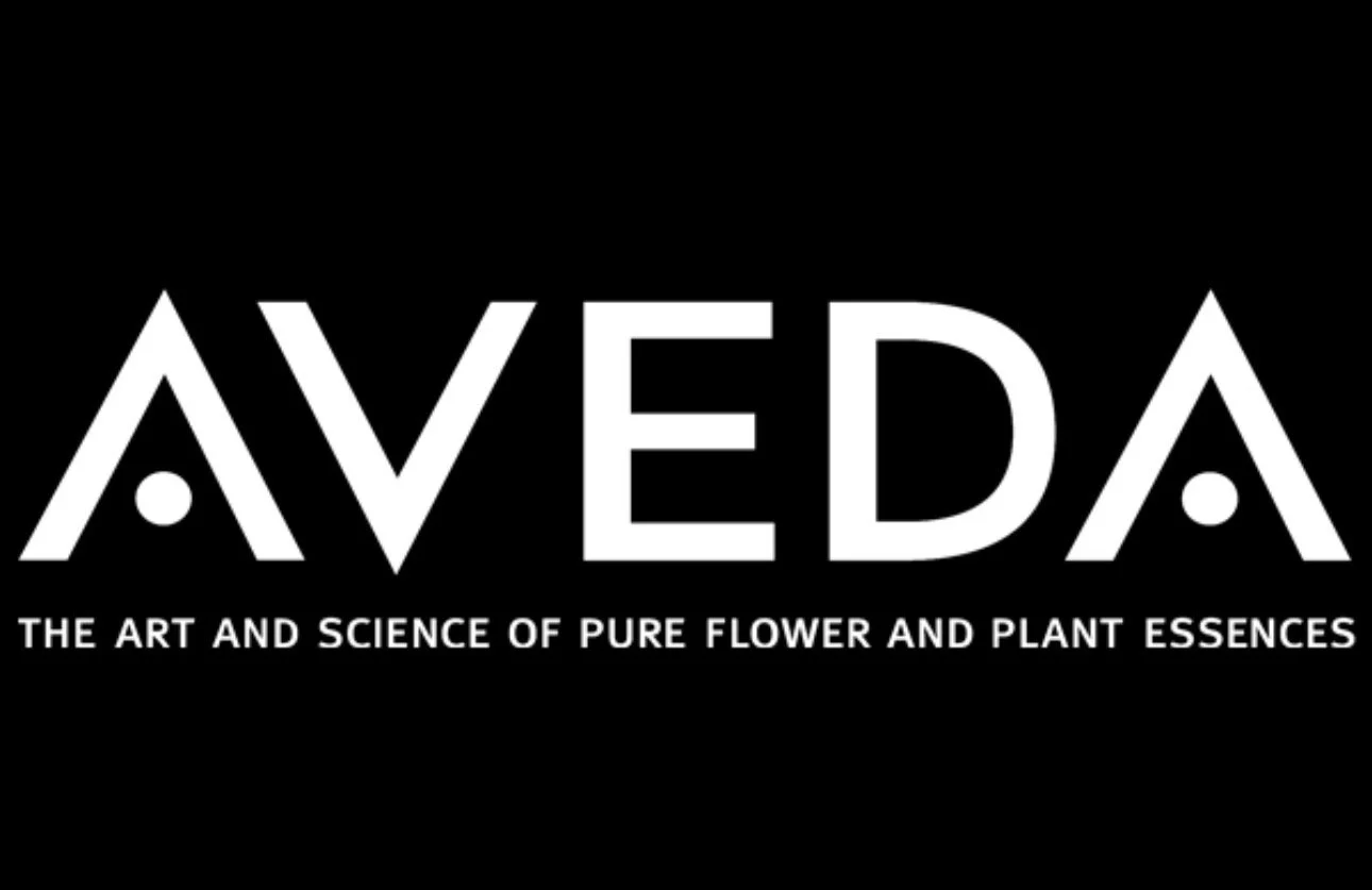 Black background with white text reading 'AVEDA' and the tagline 'The art and science of pure flower and plant essences.'