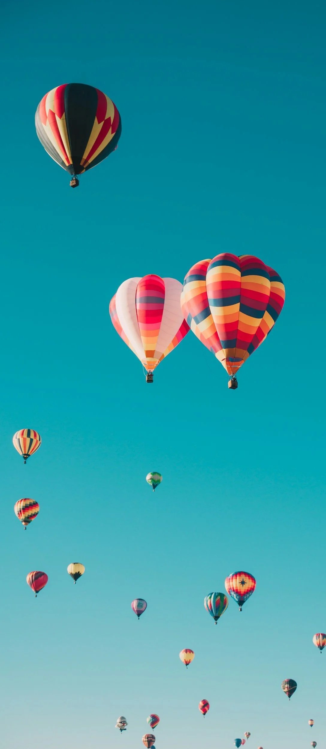 Hot air balloons rising in an open sky, symbolizing lightness, perspective, and expansion.