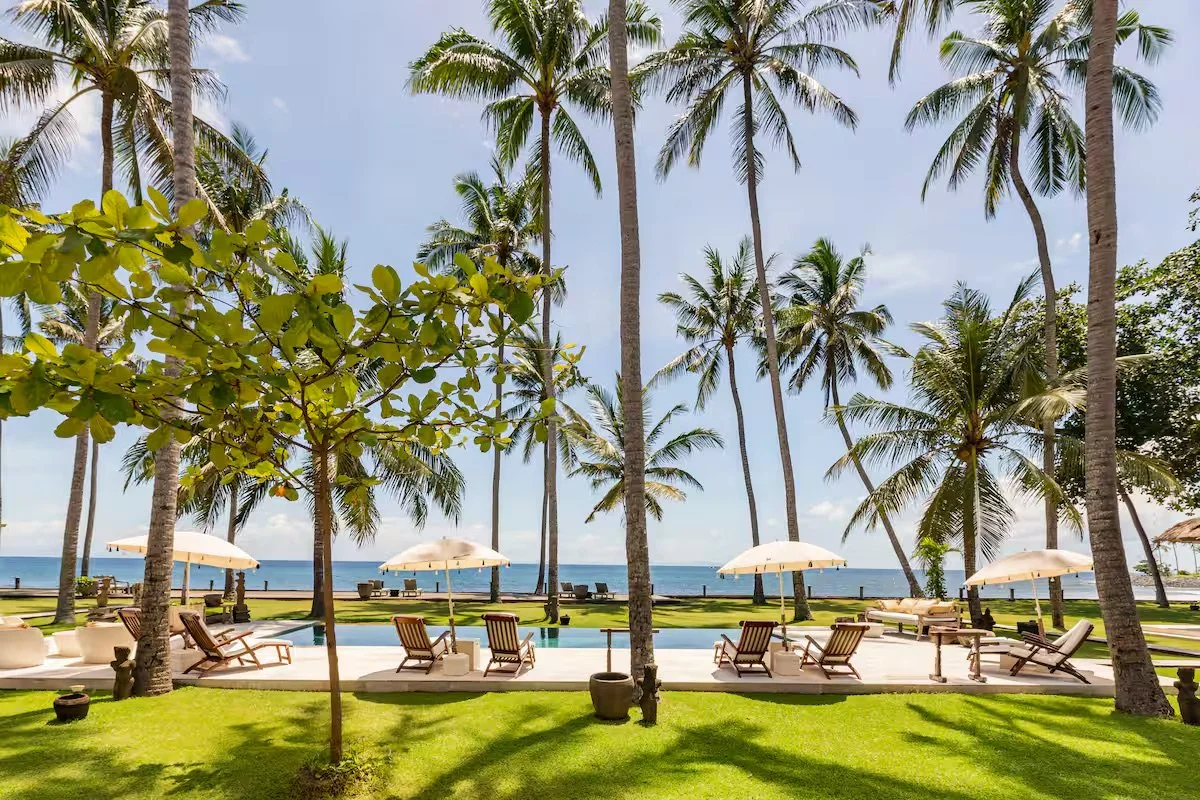 Private seafront villa in Bali with palm trees and pool, setting for a small, intentional retreat.