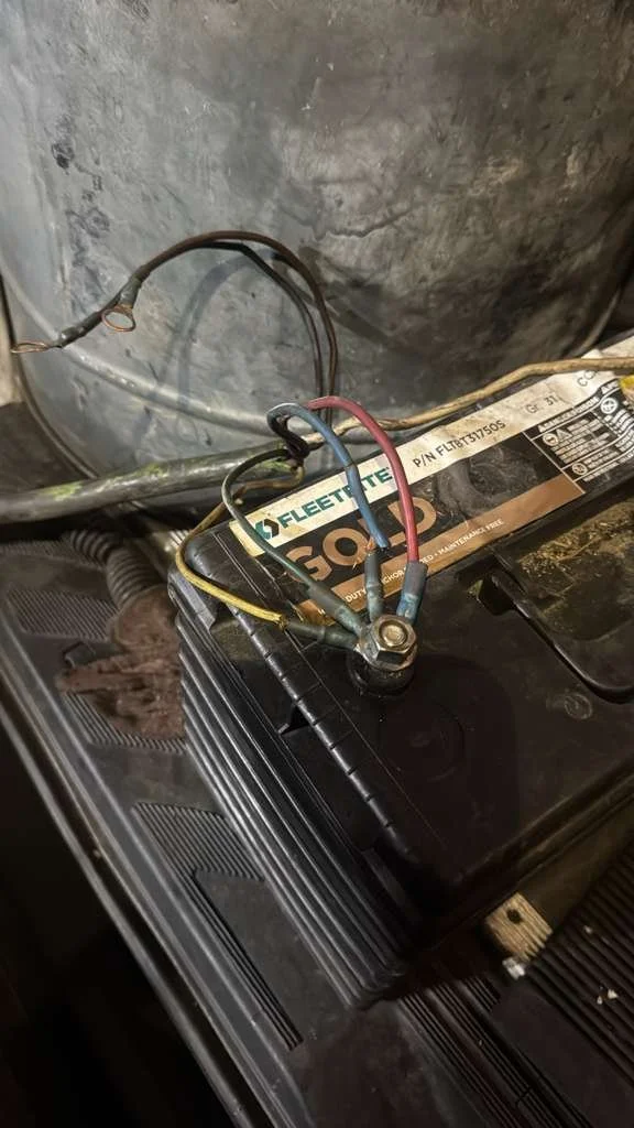 Car battery with disconnected wires in the engine compartment.