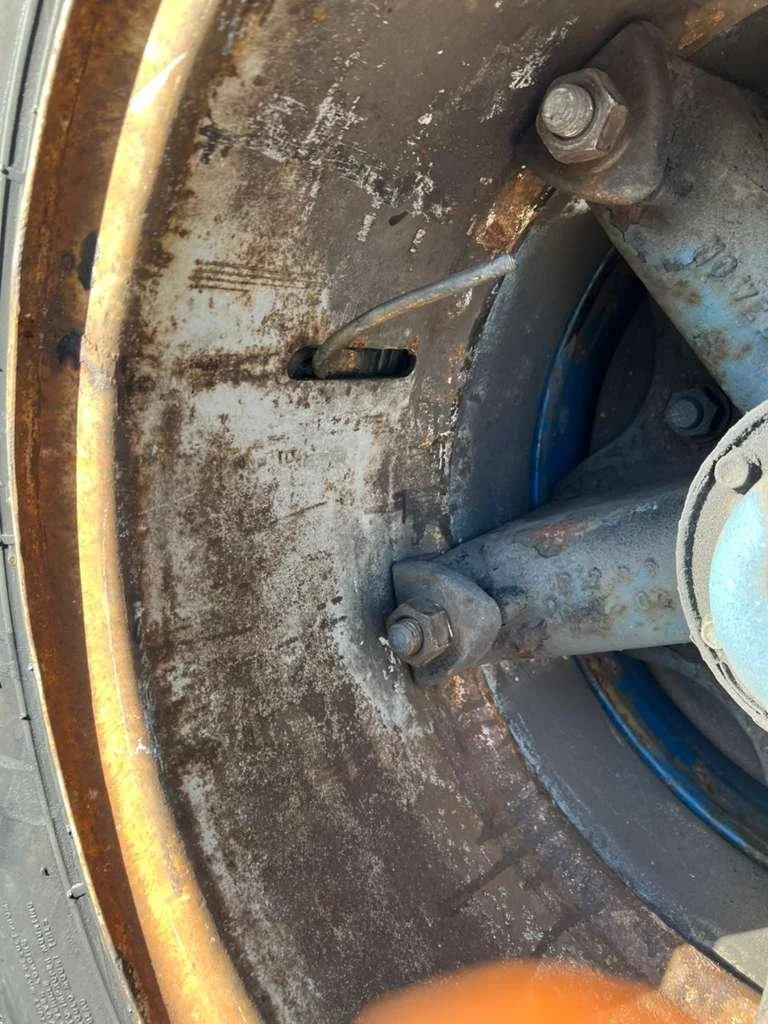 Close-up of a rusted mechanical part with bolts and a metal rotating surface, showing signs of corrosion and wear.
