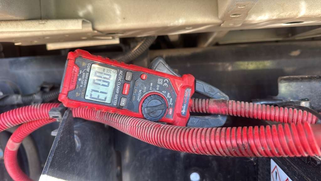 A digital multimeter, red in color, placed on a red corrugated cable, measuring 0.51 ohms.