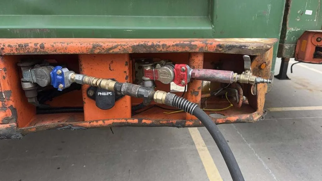 Close-up of industrial hoses and connectors attached to a rusty metal frame, with a Philips sensor in the center.